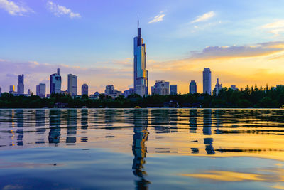 Scenic view of river and buildings against sky during sunset