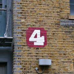 Close-up of arrow sign on brick wall