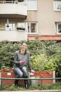 Full length portrait of happy woman with gardening equipment in garden