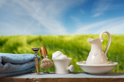 Close-up of shaving equipment and towel on table against field