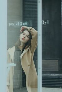 Portrait of young woman looking through window