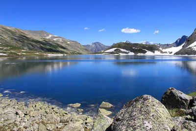 Alpine blue lake in altai surrounded by mountains and stones, sky,  summer