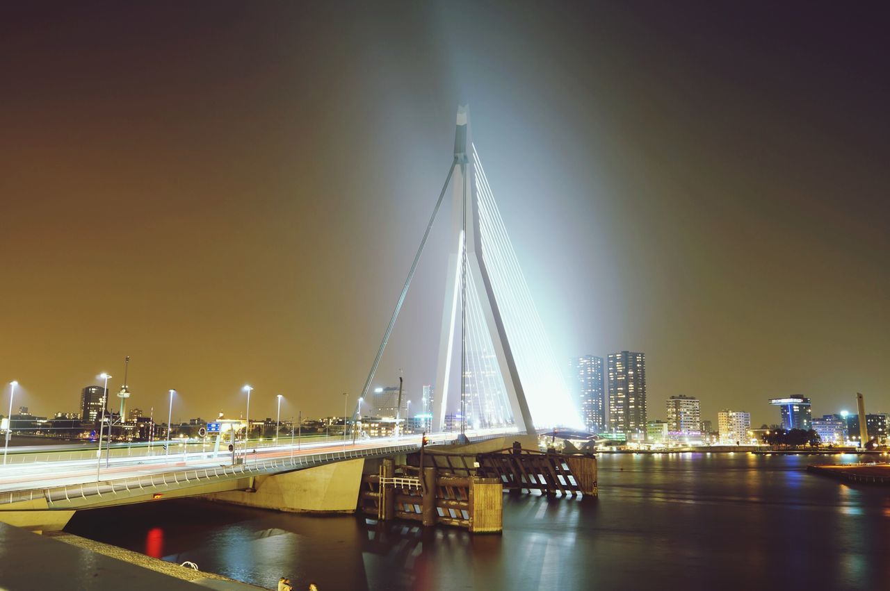 transportation, water, illuminated, architecture, built structure, city, nautical vessel, waterfront, river, night, mode of transport, building exterior, sky, copy space, bridge - man made structure, clear sky, sunset, cityscape, skyscraper, dusk