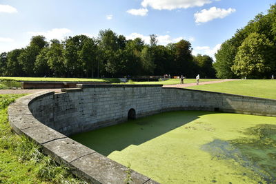 Scenic view of park by lake against sky