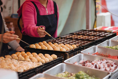 Midsection of woman preparing japanese street food at market
