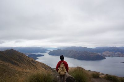 Rear view of woman on landscape against cloudy sky