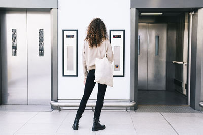 Woman with curly hair standing in front of elevator