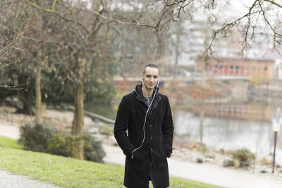 Portrait of young man standing against trees