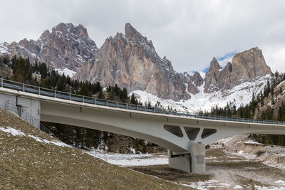 Bridge over snowcapped mountains against sky