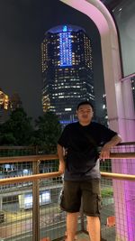 Rear view of young man standing on pedestrian bridge at night