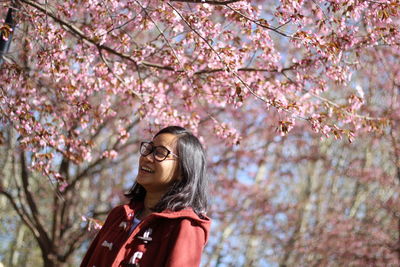 Young woman standing on cherry blossom