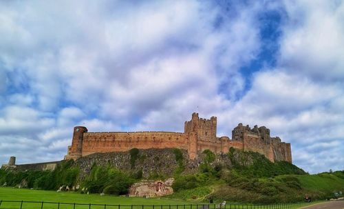 Low angle view of historic building against cloudy sky. bamburgh castle. nortumberland. uk