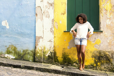 Model in a yellow dress smiling, looking and posing at the camera. 