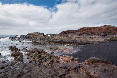 Rock formations on shore against sky