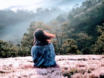 Rear view of woman sitting on field