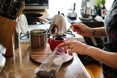 Scooping tea leaves into a teapot