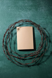Directly above shot of rusty barbed wire with book on blackboard