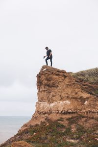 Low angle view of man standing on cliff against sky