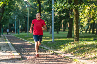 Portrait of man running on footpath in park