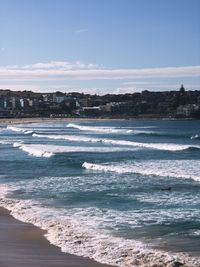 Sea waves rushing towards shore against sky