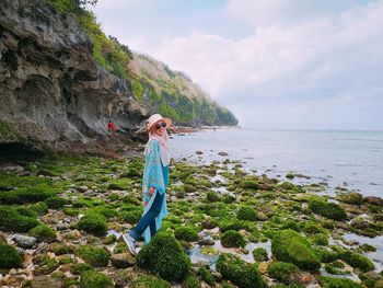 Portrait of smiling woman walking at beach against sky