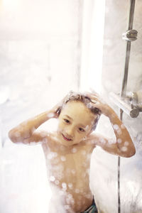 Boy taking shower seen through glass