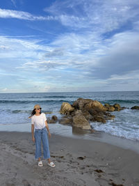 Rear view of woman standing at beach against sky