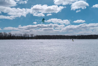 People flying over snow covered trees against sky