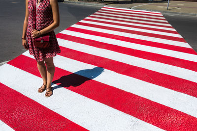 Low section of woman standing on zebra crossing during sunny day