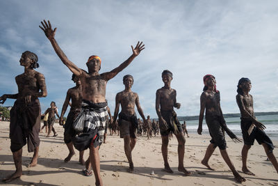 Group of people at beach against sky