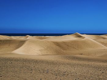 Scenic view of beach against clear blue sky