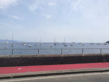 Sailboats moored at harbor against sky