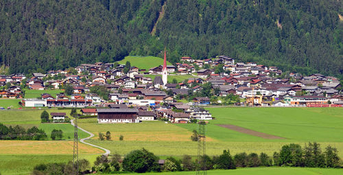 Scenic view of field by houses and trees