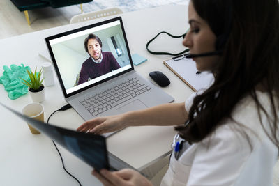 Female doctor consulting man through laptop at clinic