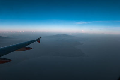 Airplane flying over mountains against sky