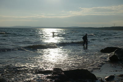 Silhouette man standing on beach against sky during sunset