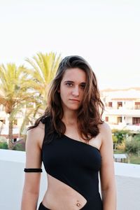 Portrait of beautiful young woman wearing swimsuit against clear sky