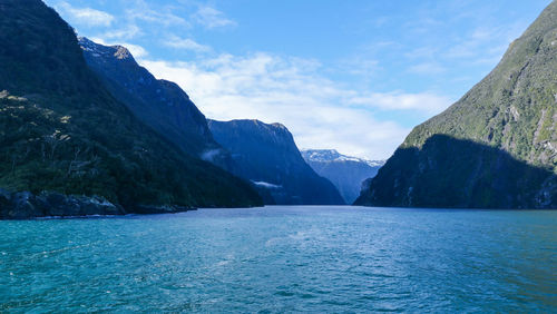 Scenic view of sea by mountains against sky