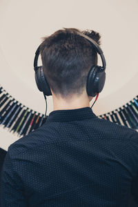 Rear view of teenage boy listening music while standing against decoration