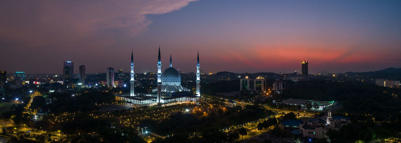 Illuminated cityscape against sky during sunset