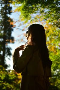 Woman standing by tree against plants