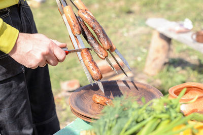 Midsection of man preparing sausages at yard