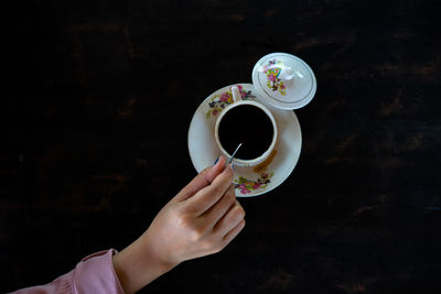 Cropped hand holding coffee on table