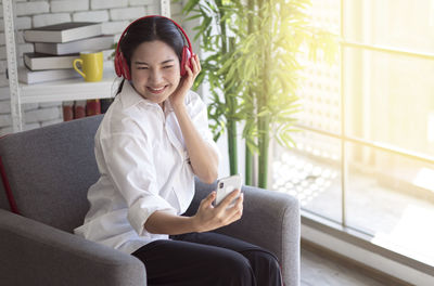 Young woman using phone while sitting on sofa