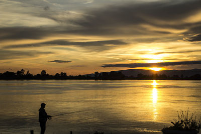 Silhouette person on beach against sky during sunset