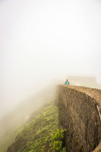 Rear view of man hiking on fort during foggy weather