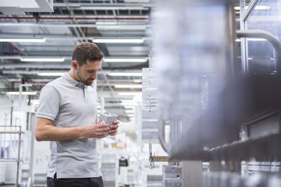 Man with tablet in factory shop floor examining products