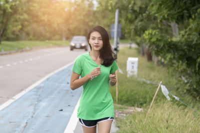 Young woman standing on road against trees