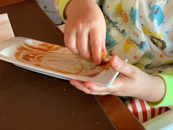 Midsection of boy eating food while sitting on high chair at home