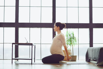 Side view of young woman exercising in gym